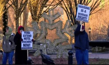 Demonstrator holds a sign in downtown Asheville calling on FEMA to extend temporary housing assistance to victims of Helene currently staying in hotels after the storm.