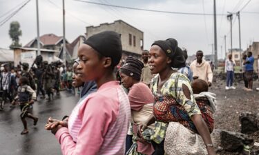 Residents react as members of the M23 armed group walk through a street of the Keshero neighborhood in Goma