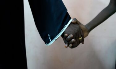 An 11-year-old rape survivor holds his mother’s hand after visiting a psychologist and social worker who are helping him deal with the trauma of rape.