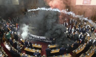 Smoke fills Serbia's parliament on March 4 as lawmakers unroll a banner that reads: "Serbia rises up to bring down the regime."